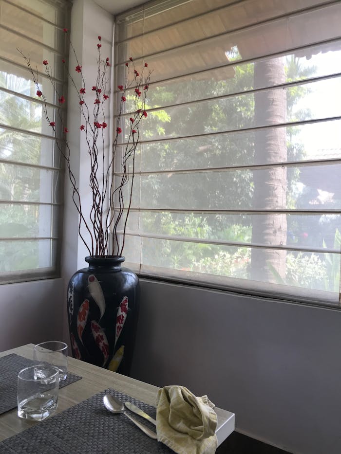 Stylish indoor dining area featuring a decorative vase and table setting with natural sunlight.